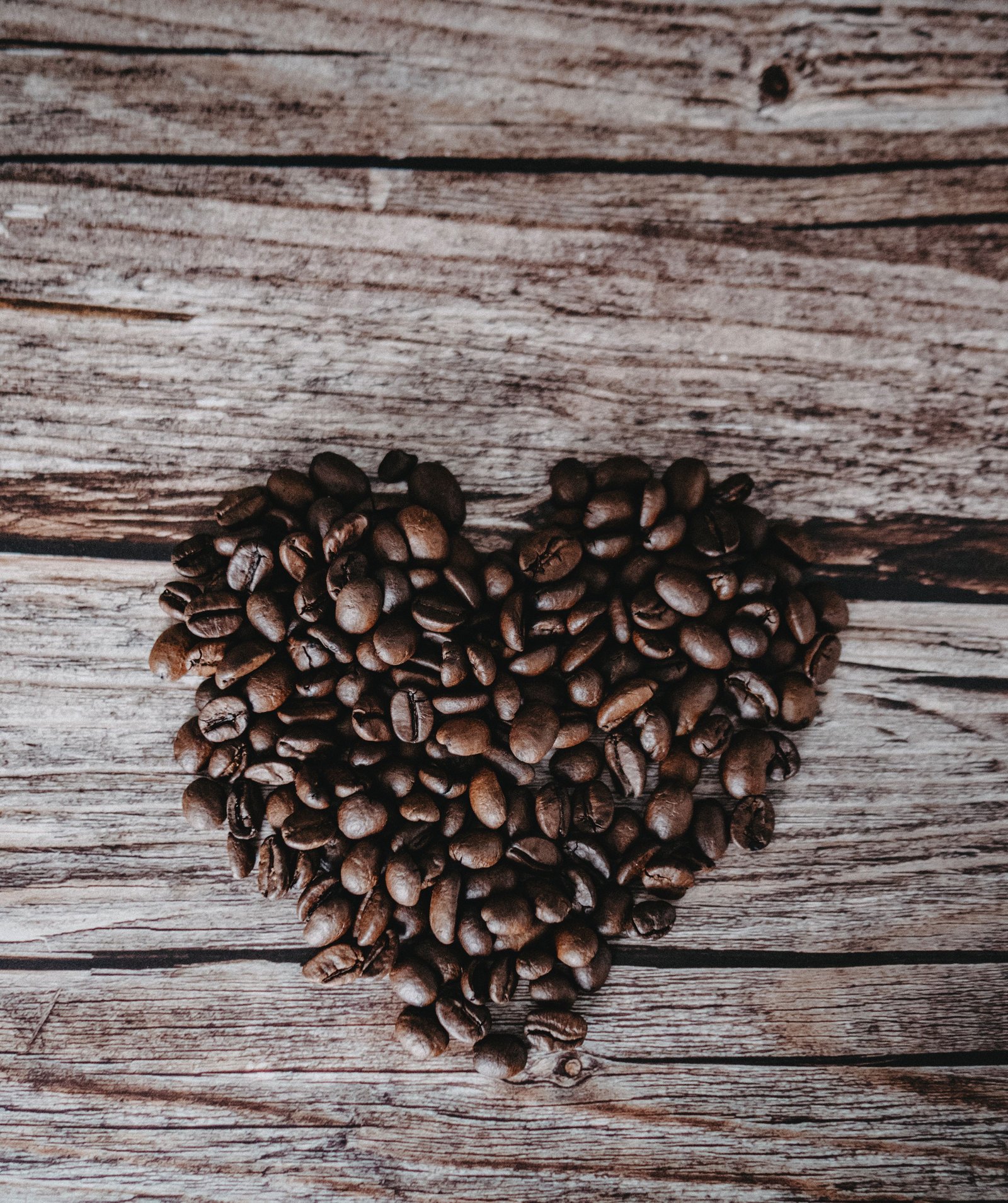 Coffee beans arranged in a heart shape on a wooden table